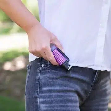 Slim pepper spray canister clipped to a jeans waistband